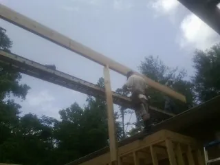 Carpenter setting a ridge beam over a new addition frame — Ice Dam Removal by Roofing Brothers in Christiana