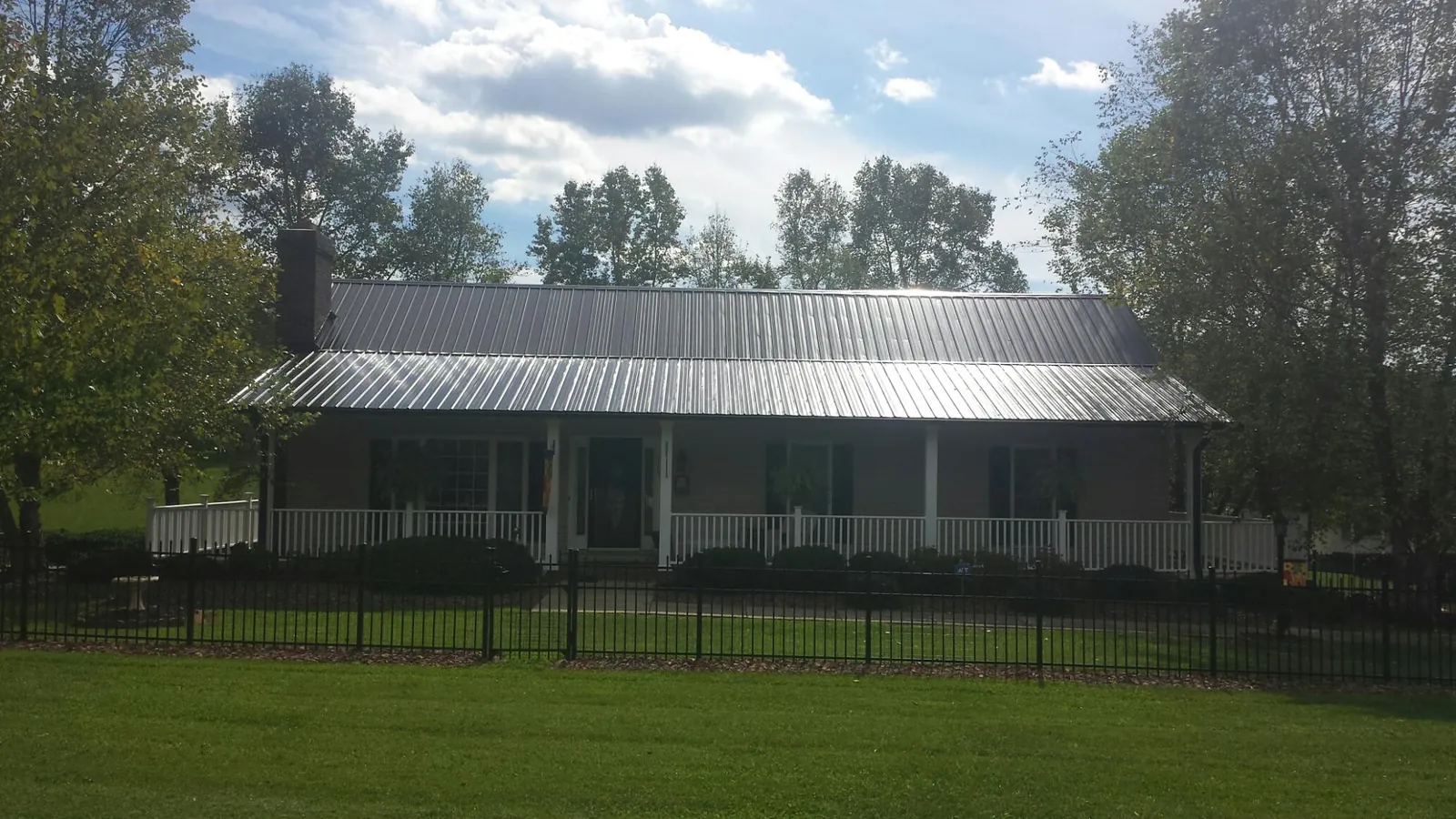 Gray metal roof on a brick ranch with a full width front porch — Gutter Guard Installation work by our crew in Christiana
