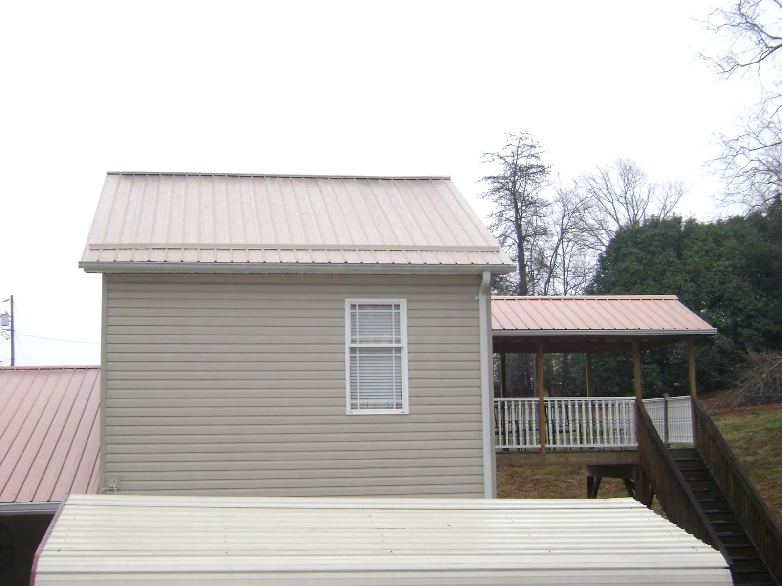 Tan metal roofs on a two story addition and attached porch, from a Roof Replacement job in Christiana