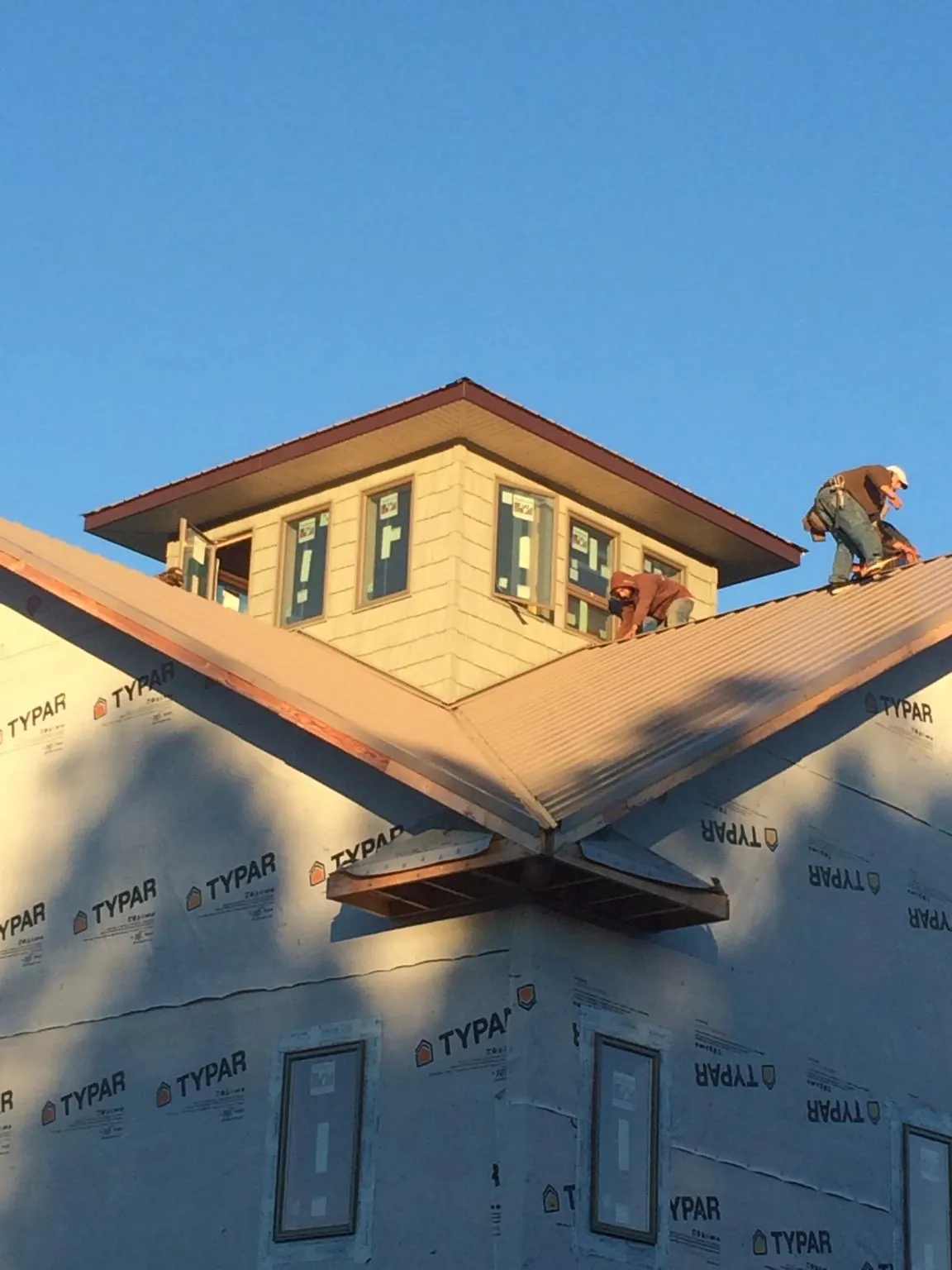 Roofers working around a rooftop cupola on a new metal roof at sunset — Roof Waterproofing in Christiana by Roofing Brothers